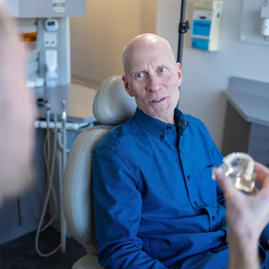Senior patient conversing with his dental team