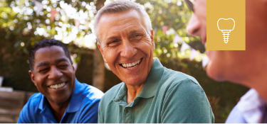 Men sitting in circle outside and smiling