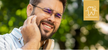 Man with glasses rubbing jaw